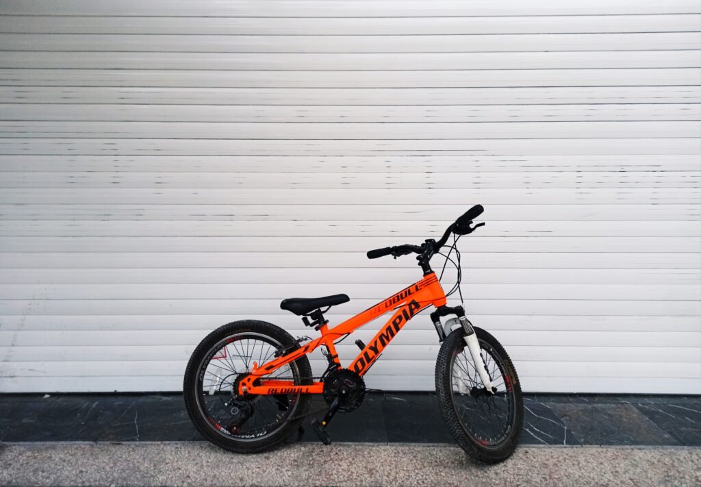 Vibrant orange bicycle resting on a seamless white backdrop, showcasing minimalist design.