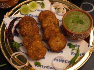 Crispy Indian fritters served with mint chutney on a decorative plate.