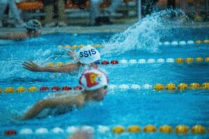 Energetic swimmers competing in a butterfly stroke race at an indoor swimming pool.