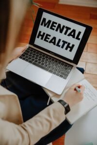 A woman engaging in an online mental health session on a laptop.