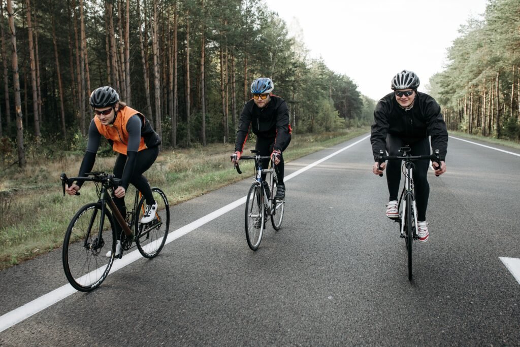 Three cyclists are enjoying a ride on a scenic forest road during the day.