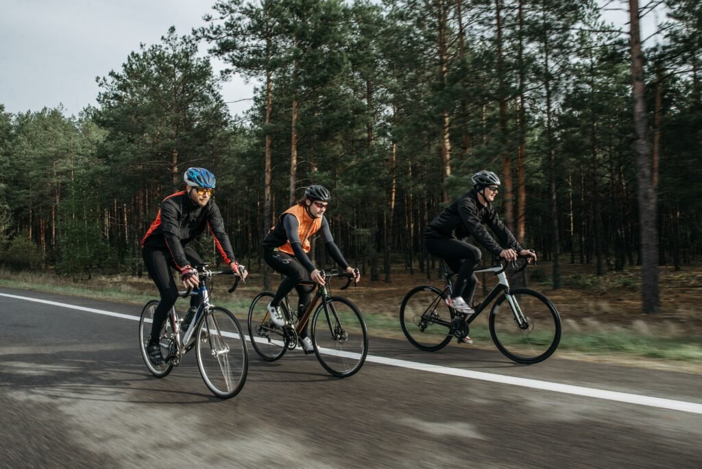 Group of cyclists riding on a road beside a forest, showcasing the thrill of outdoor biking.