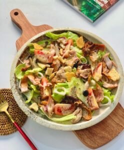 A fresh and healthy chicken and vegetable salad served on a wooden board, perfect for lunch or dinner.