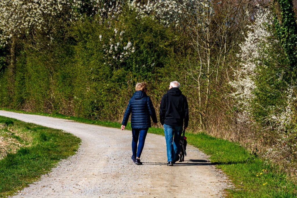 Couple walking a dog on a spring day in Coesfeld, surrounded by blooming trees.