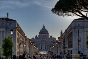 A vibrant view of St. Peter's Basilica along a bustling street in Vatican City, Italy during dusk.