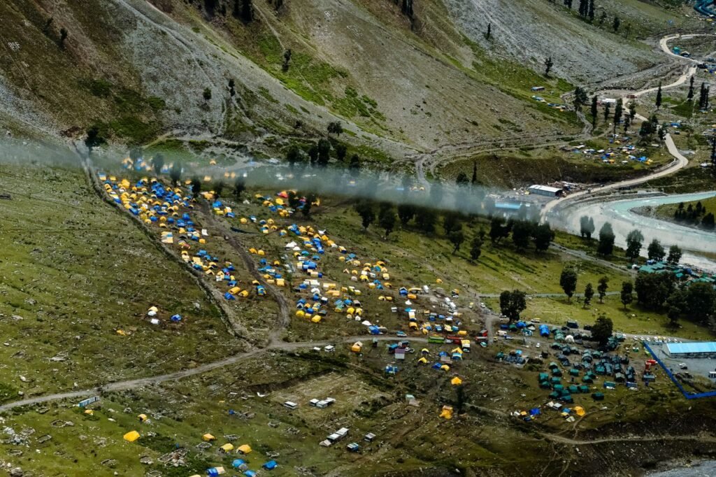 Aerial view of colorful tents set up in a mountainous region, showcasing vibrant camping community in lush terrain.