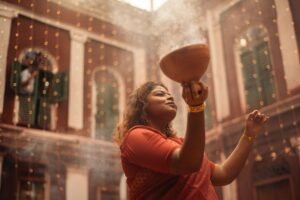 A woman in traditional attire performing a ritual in a decorated festive setting.