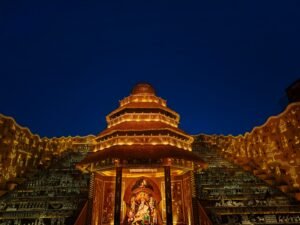 A beautifully lit Durga Puja pandal in Kolkata, showcasing Hindu art and culture under a night sky.