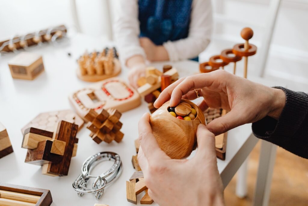 Close-up of hands engaging with wooden brain teasers on a table indoors.